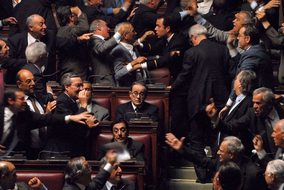 Diputados gesticulando y discutiendo en el recinto de una cámara legislativa